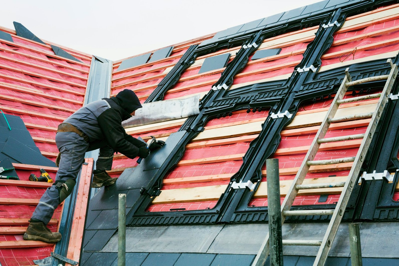 A roofer replacing the tiles on a house roof.