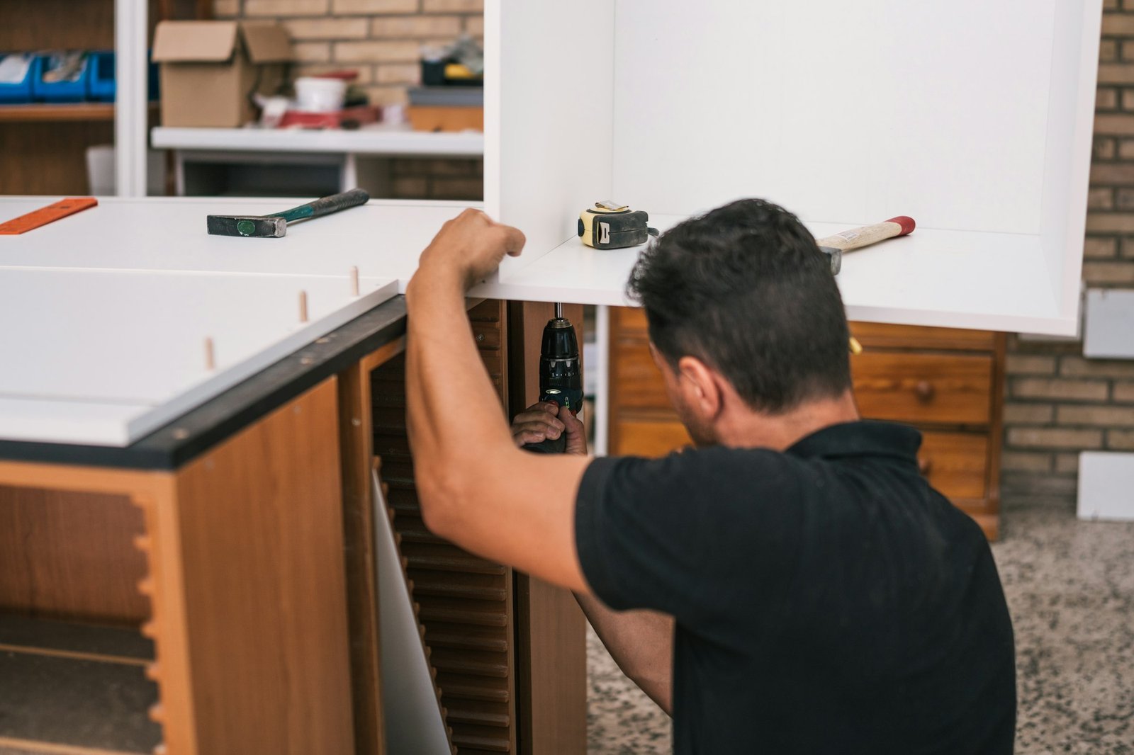 Worker using a drill to build a kitchen furniture